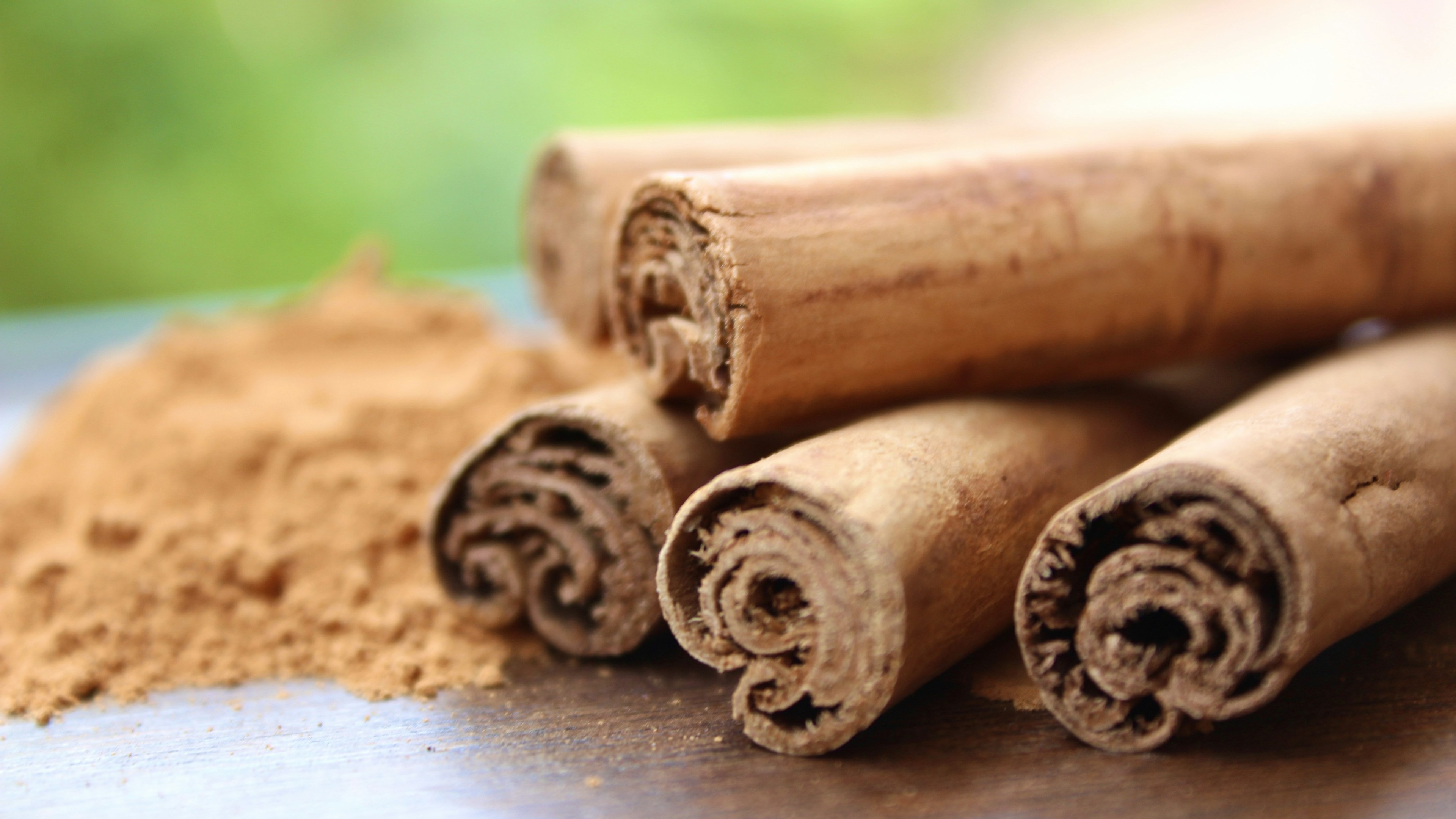 Close up of 5 sticks of cinnamon next to powder