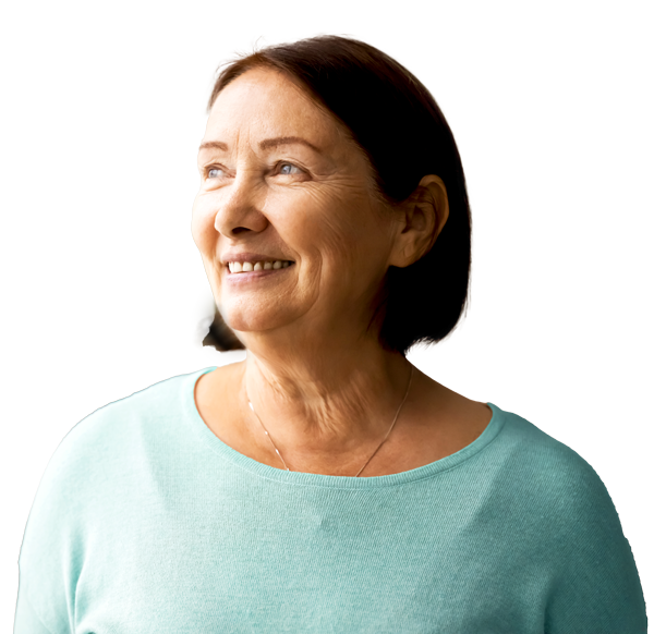 Smiling older woman with short dark hair wearing a light blue top, standing outdoors.