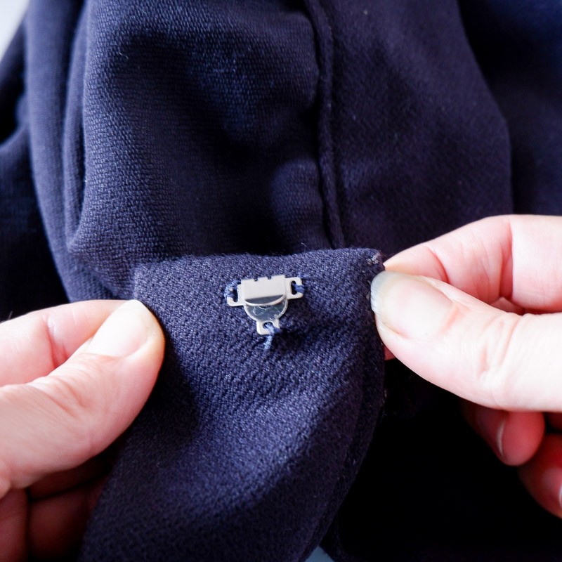 Picture of a hook sewn onto a waistband that has a zipper