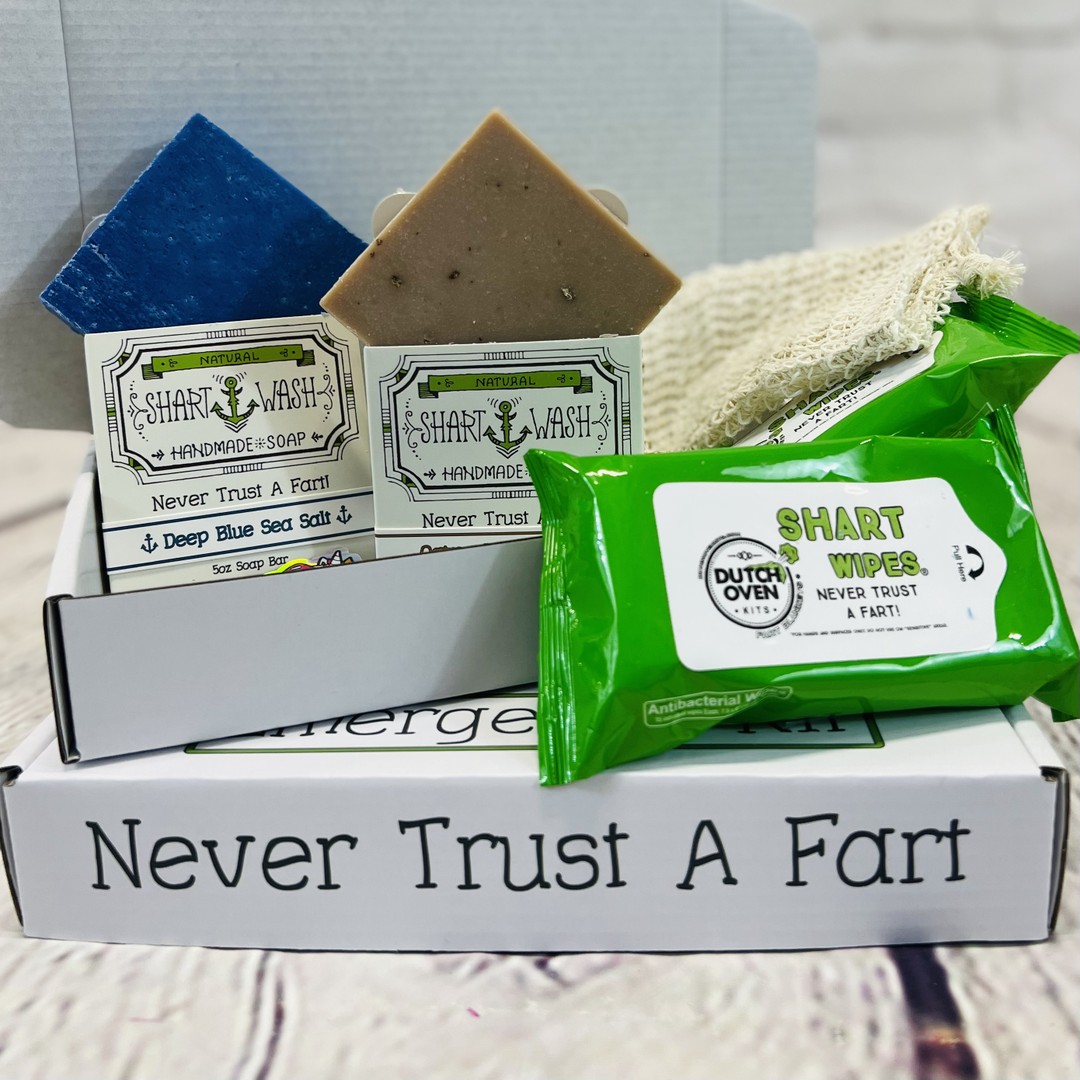 Picture of a Shart Wash Emergency Kit Gift Box open displaying a bar of lavender lemongrass soap, jasmine lime soap, 2 packs of shart wipes and a tan soap bag