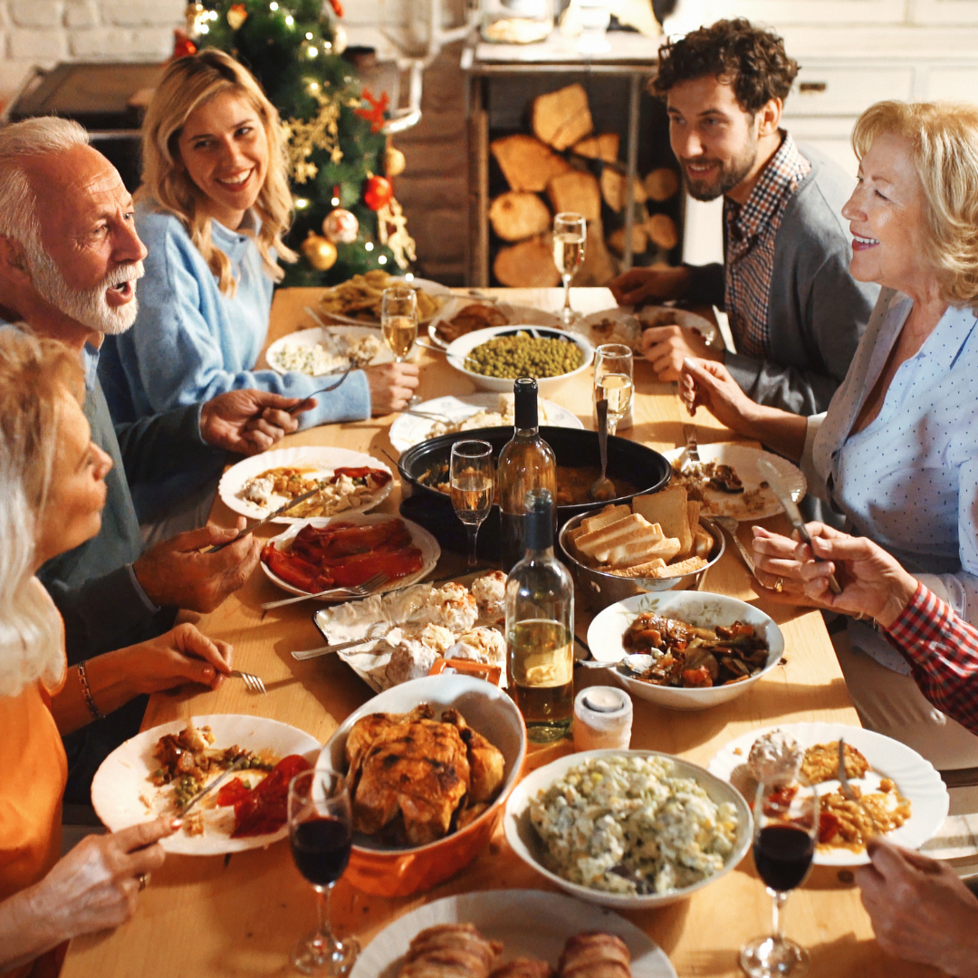 Family and friends gathered around a cozy holiday dinner table sharing laughter and home-cooked food, capturing the warmth and joy of hosting at home — part of the Dinner Hosting Essentials series from Roots To Table on creating meaningful gatherings.
