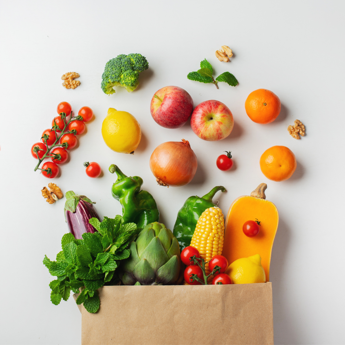 healthy fruits and vegetables falling out of a brown paper bag