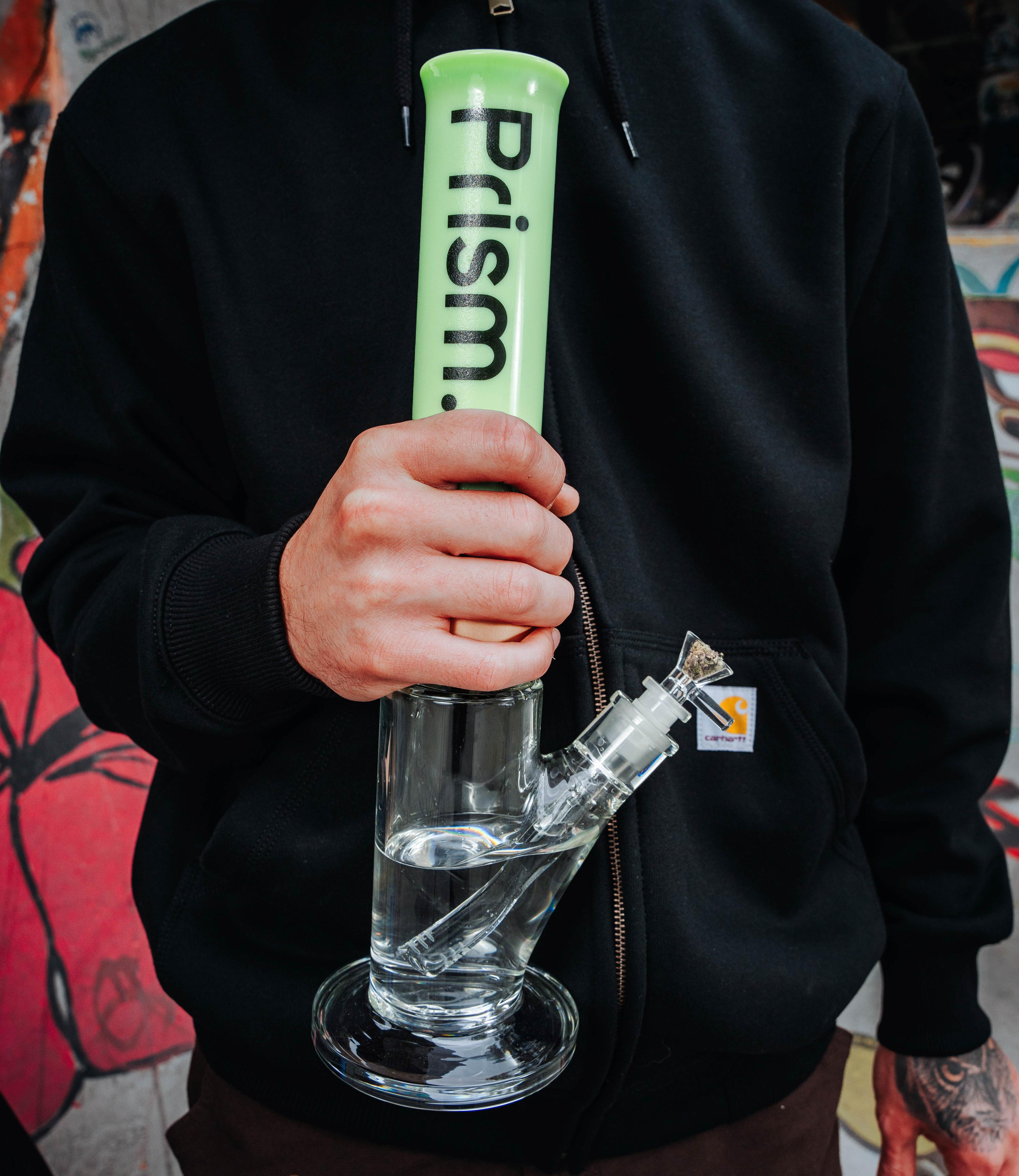 Skateboarder holding the new Prism Single Stack Straight Tube bong with a mint mouthpiece. Showcasing the sleek, 7.1" tall straight tube base design in a lifestyle context.