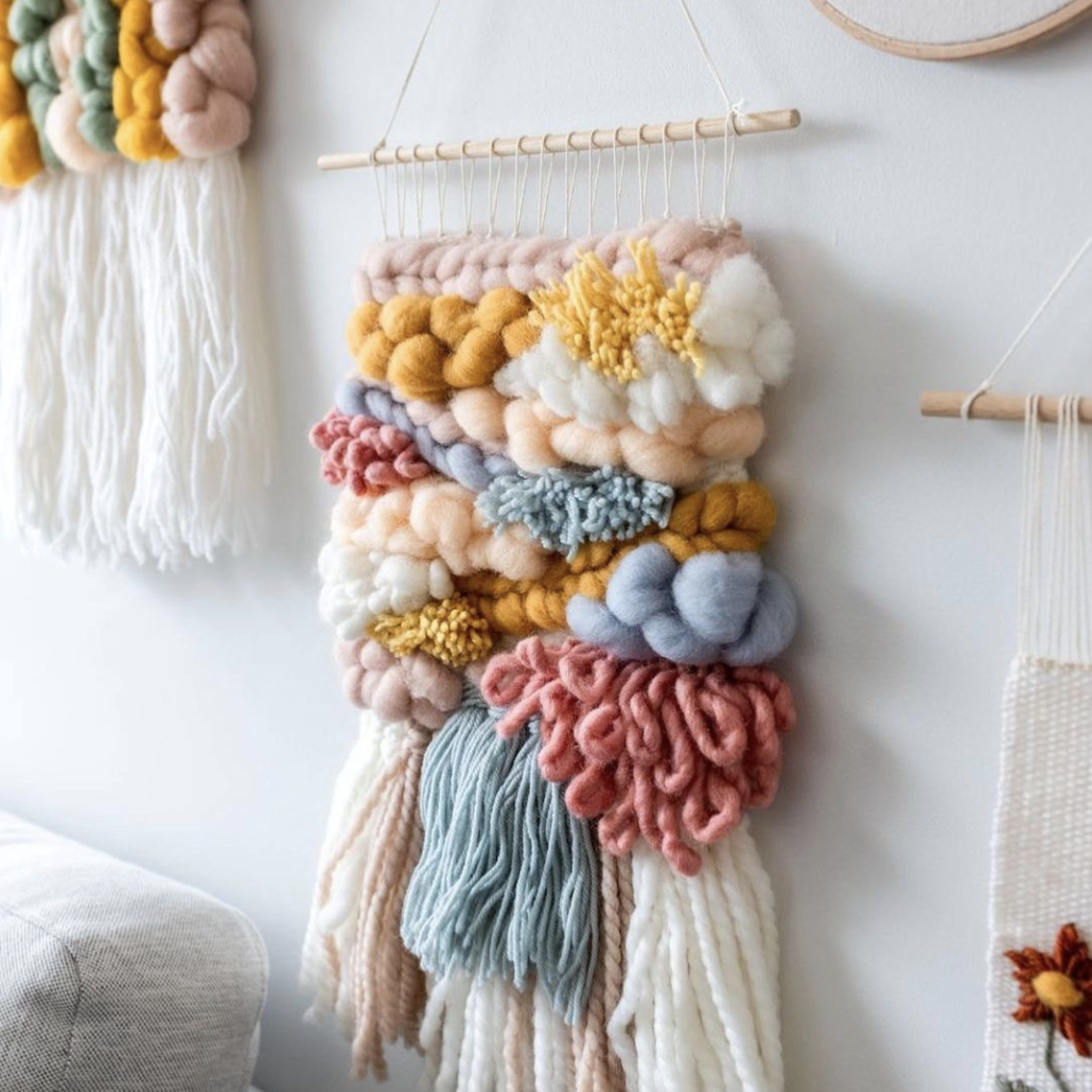 This image shows a beautiful weaving hanging on the wall, surrounded by other weavings.