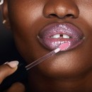 Deep skin tone model applying Pink Pout to lips