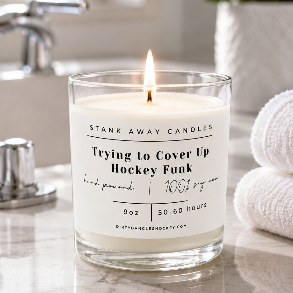 A white scented hockey candle in a bathroom with white towels. Trying to cover up hockey funk