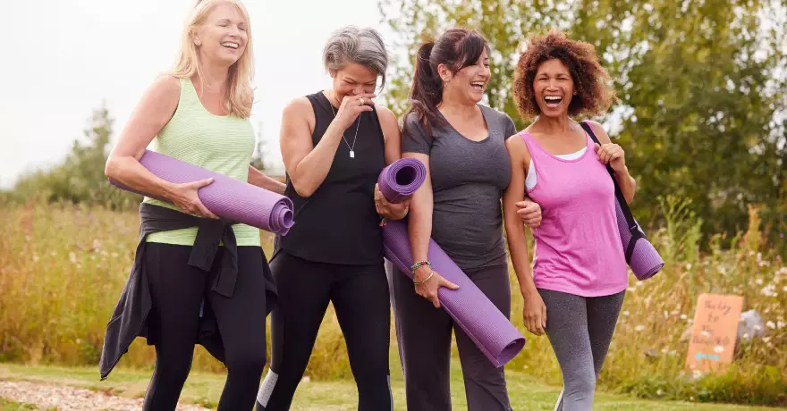 4 women standing with yoga mats