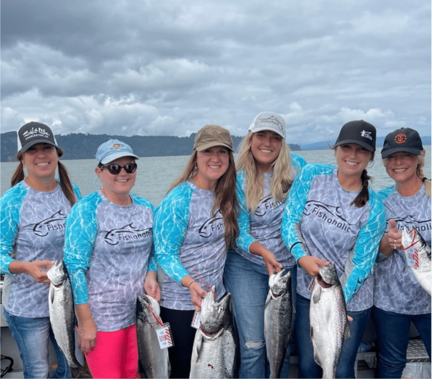 Women wearing Fishoholic fishing shirts holding up the fish they caught on the water