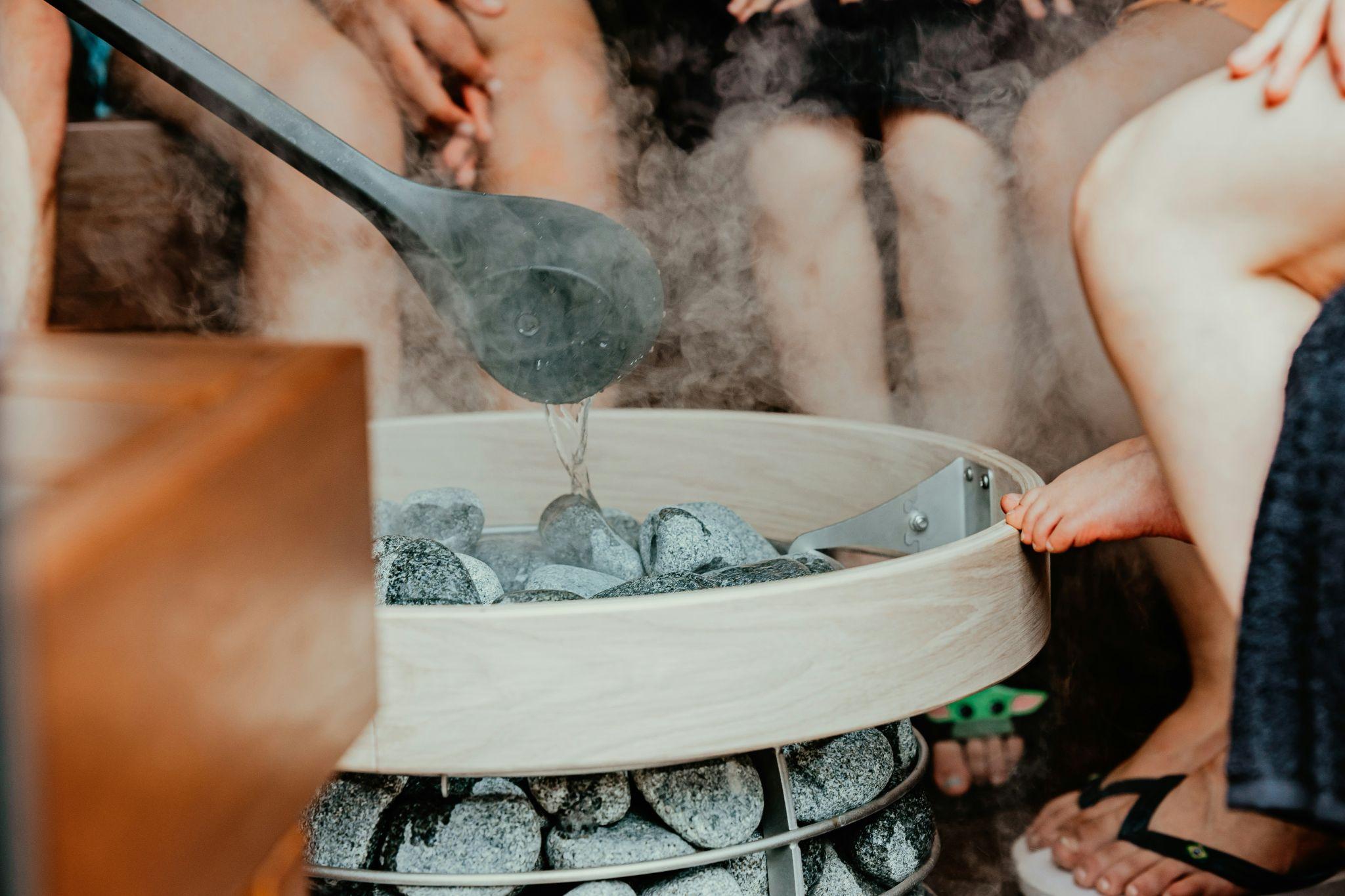 Water being poured over hot sauna rocks to create steam