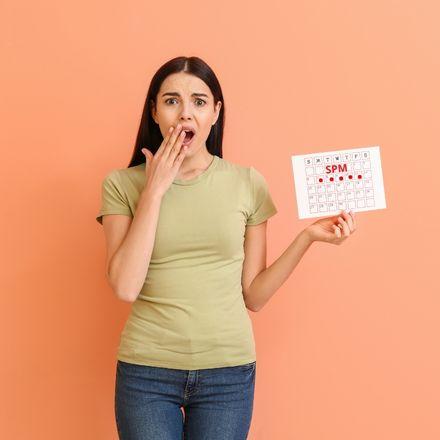 jeune femme qui tient un calendrier de règles indiquant le SPM