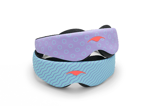 A purple sleep mask for kids with a circles design on top of a blue sleep mask for kids with a squiggles design.