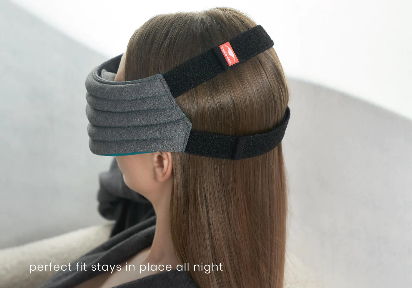 The back view of a girl’s head wearing the best weighted sleep mask for side sleepers. The mask is secured to her head with 2 black bands.