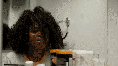Black woman seeing her hair and screaming in the mirror.