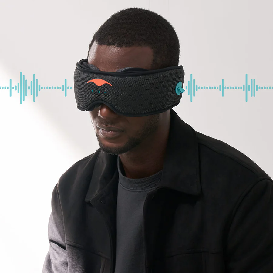 A man wearing a black Bluetooth sleep mask with headphones. Sound waves are emanating from the speakers.