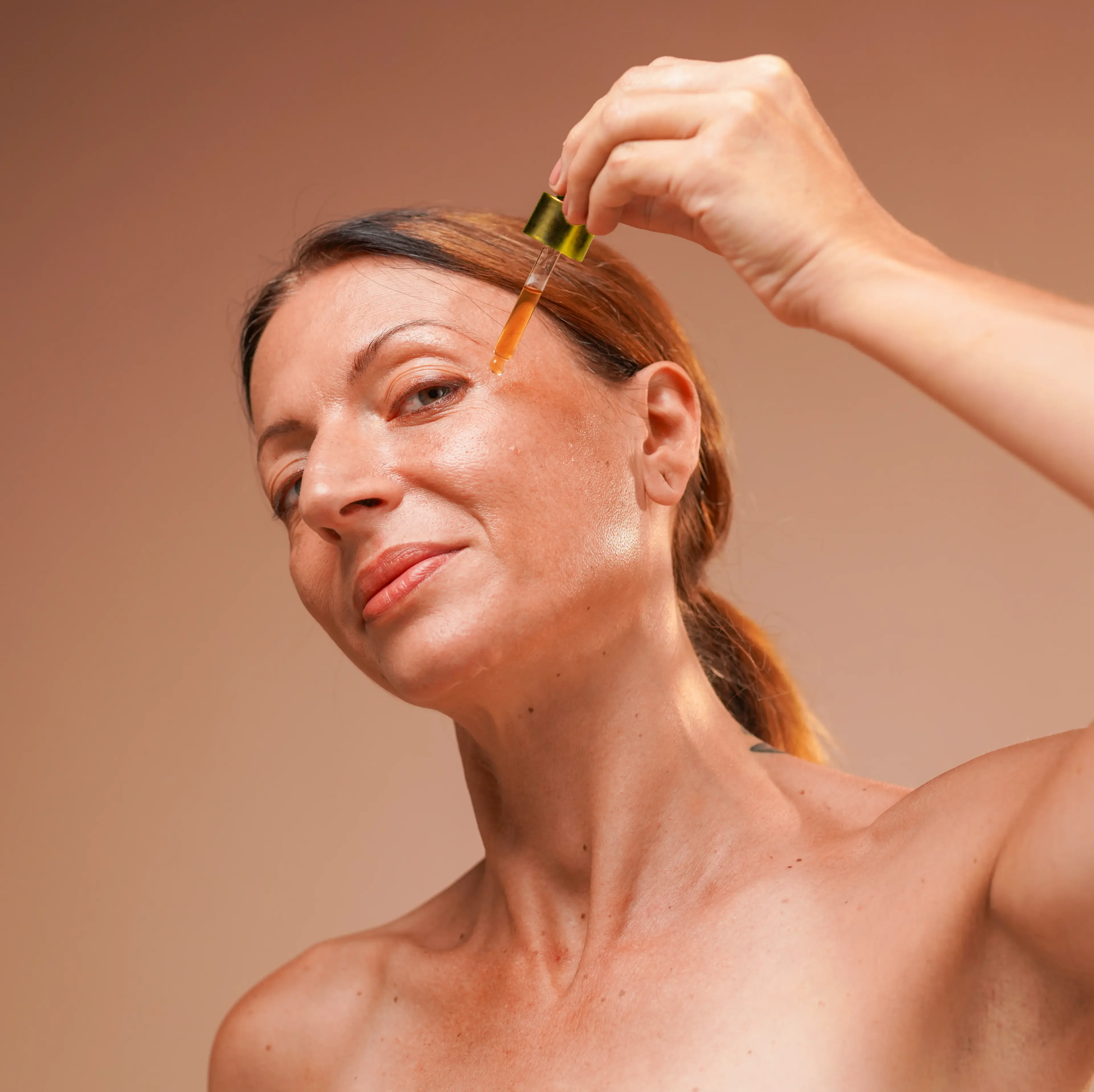woman applying oil/serum on her face with a dropper
