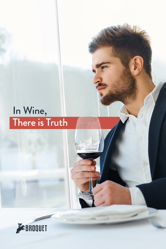 man looking out the window, holding a glass of wine, broquet logo, text reads: In wine, there is truth