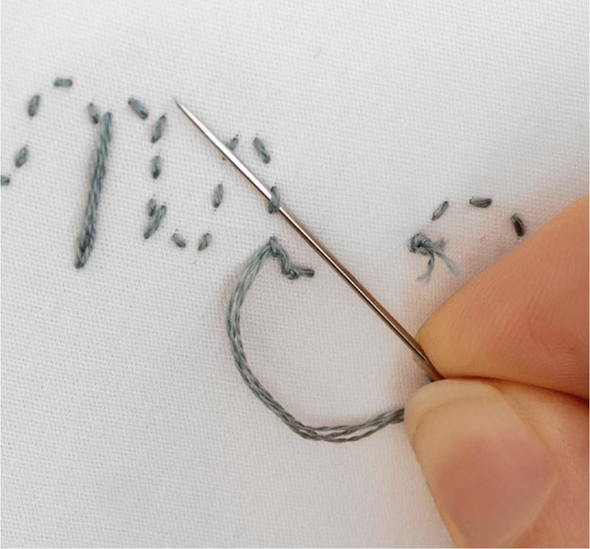 An embroidery needle goes under the back of a stitch.