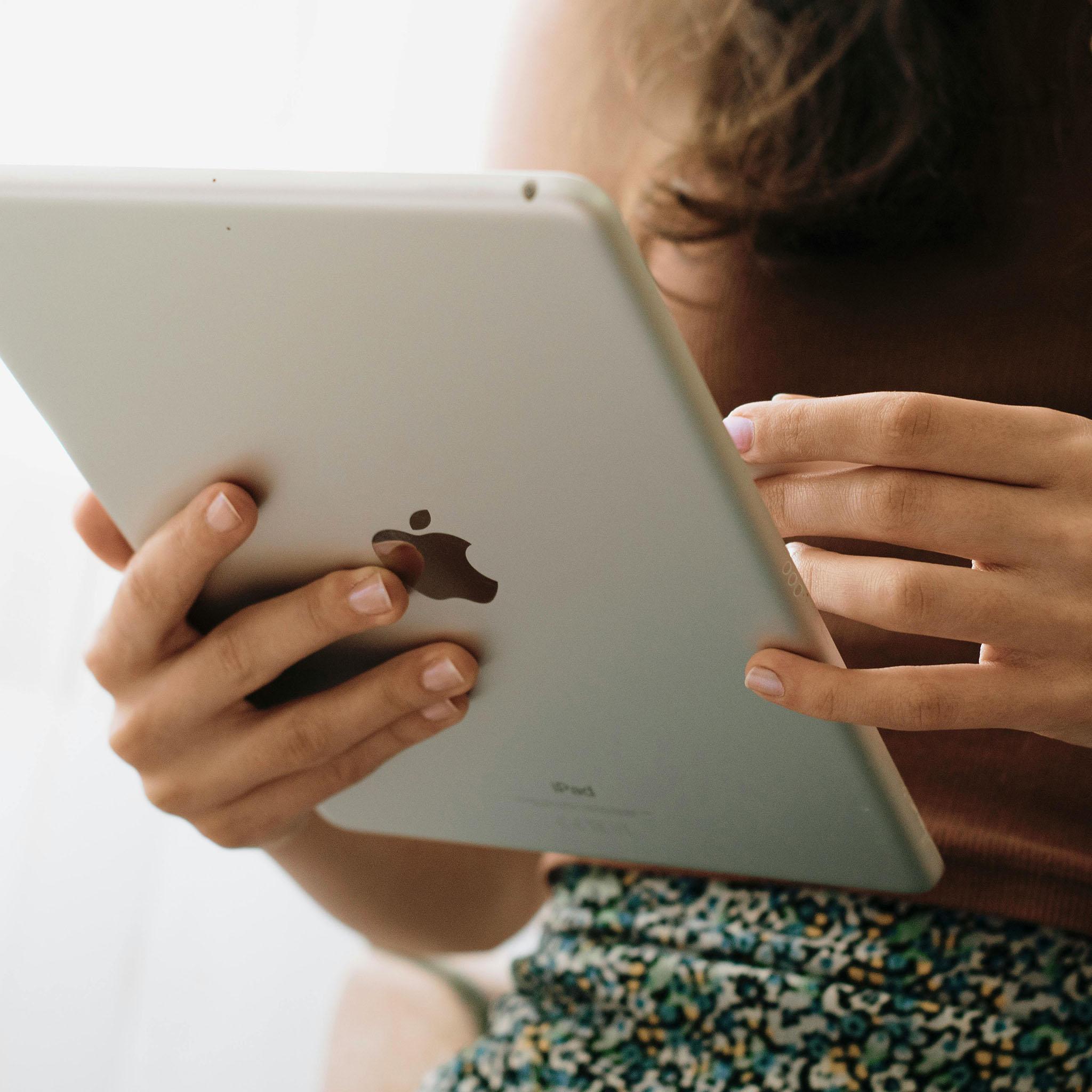 Person holding iPad showing digital planner layout for monthly weekly and daily planning