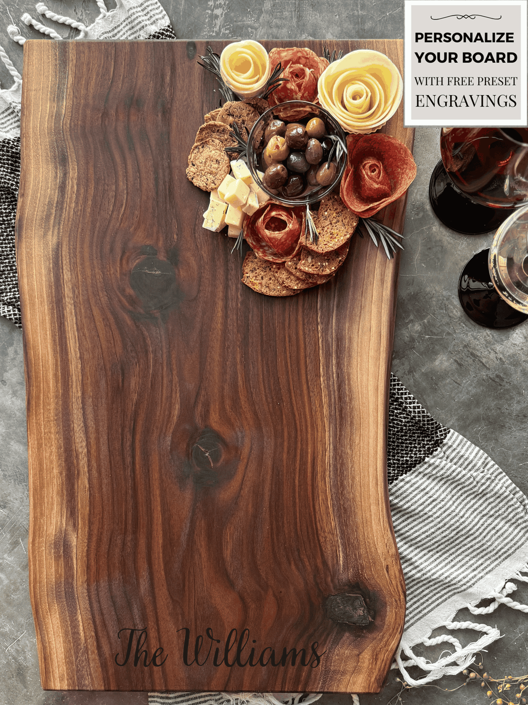 Black Walnut Live Edge Rustic No handle 26x 13 Cheese Board and cutting board with a beautiful arrangement of meats, cheeses, fruits and other foods with a large personalized engraving.