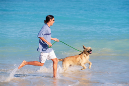 DOG AND OWNER RUNNING ON BEACH