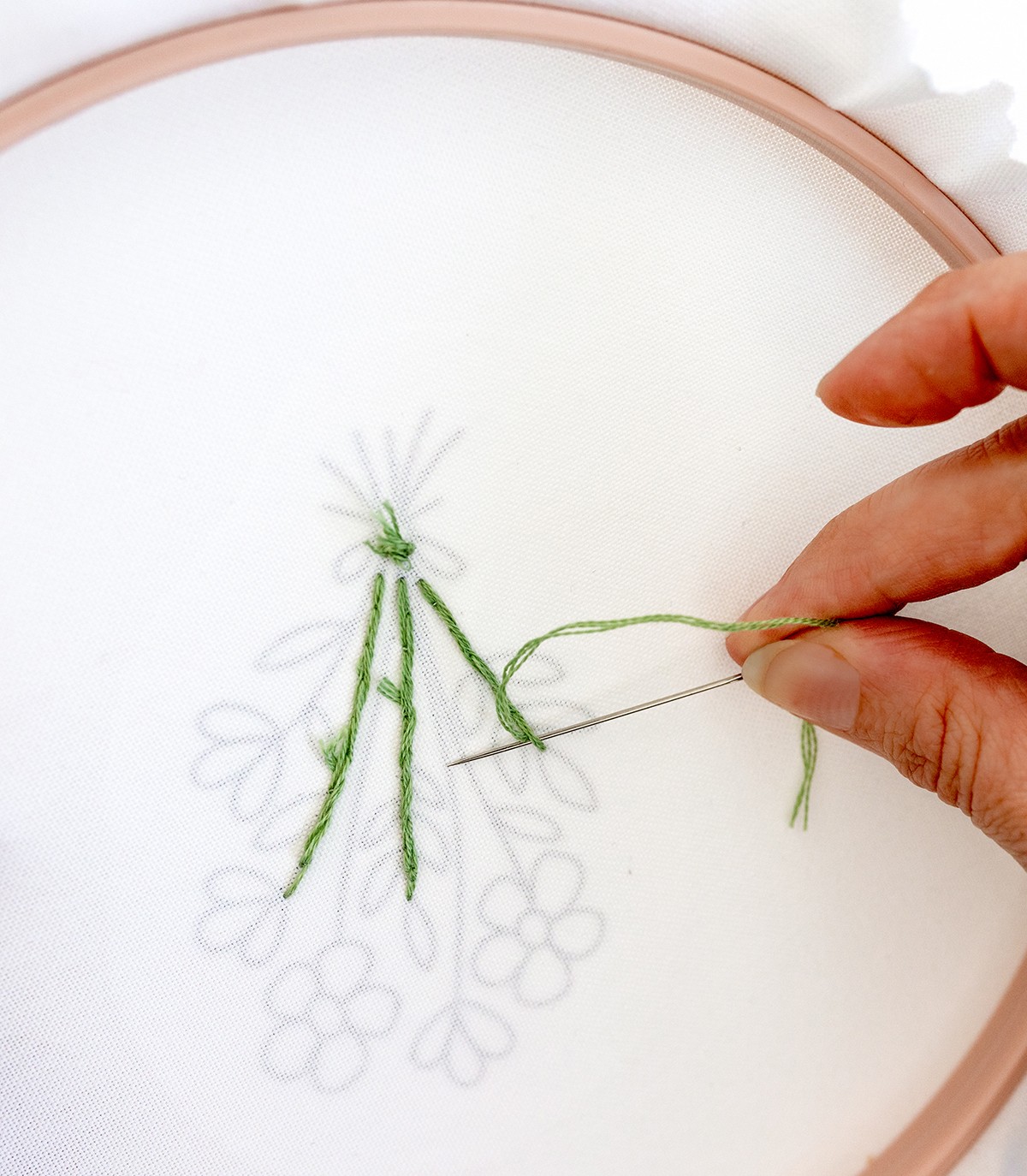 A needle is pushed under a stitch.