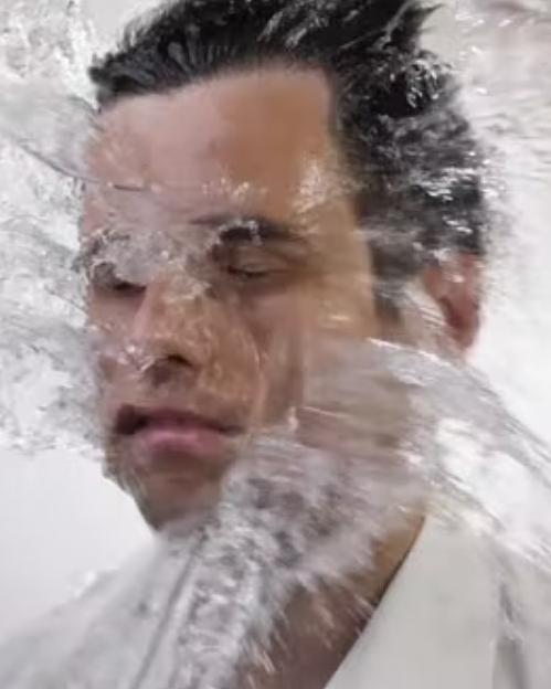 Man being splashed in the face by water, illustrating the unpleasant splashback that a bong's ice catcher or splash guard prevents during large rips.