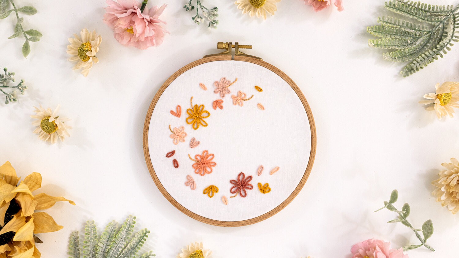 This images shows the Free embroidery pattern - Petal Breeze, is placed surrounded by flowers.