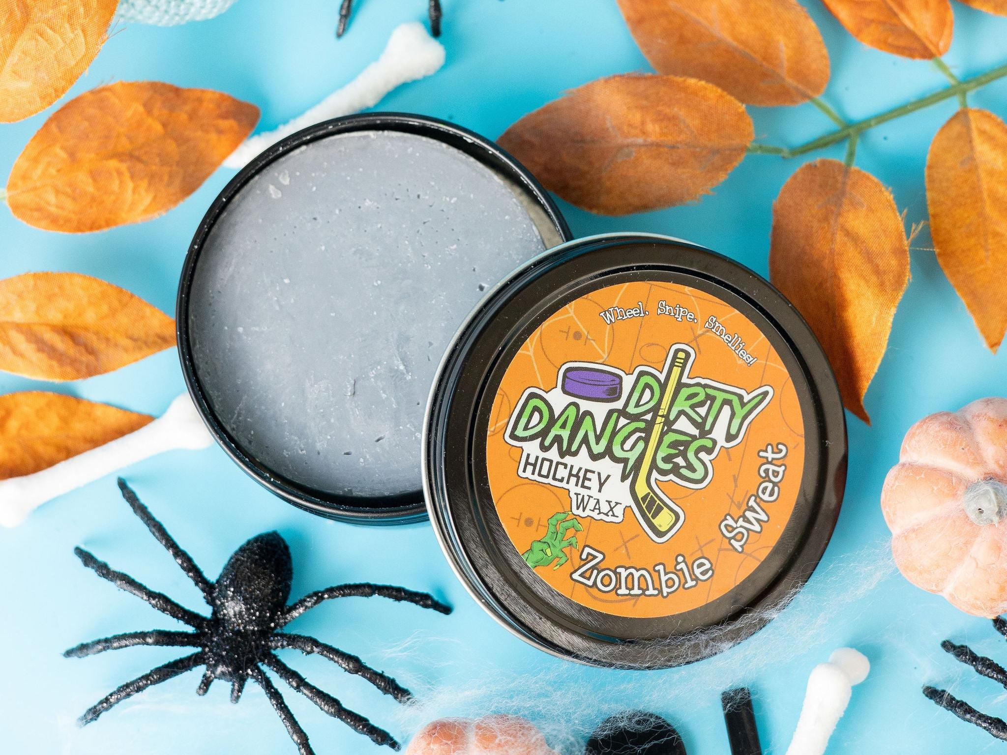 A tin of Halloween dirty dangles hockey zombie sweat pumpkin spice stick wax on a spooky background with spiders and pumpkins