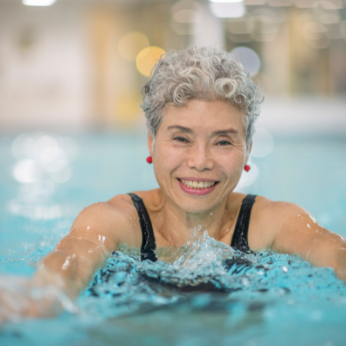 senior woman smiling as she swims in a pool.