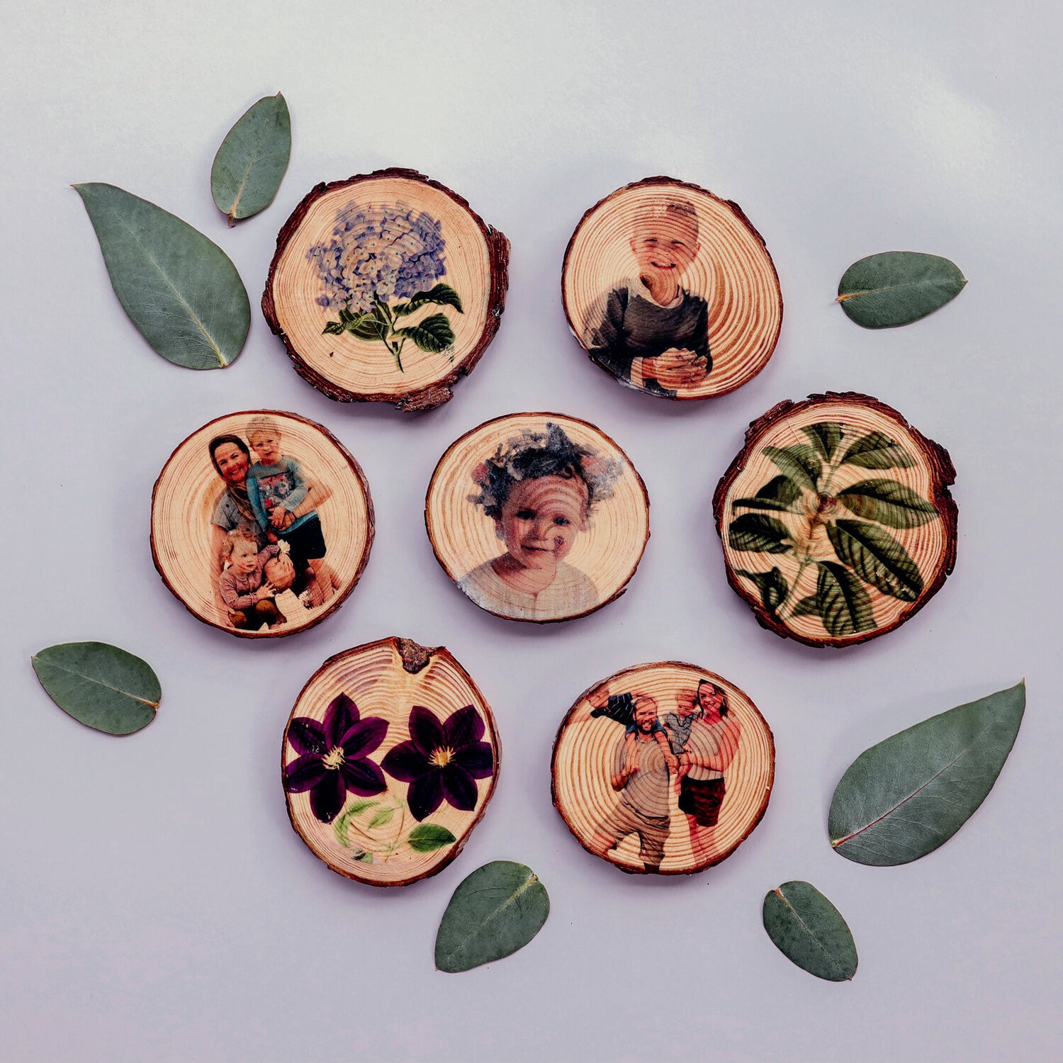 Wooden blocks with photos on them lie on a table with leaves around them.