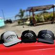 3 dirty dangles hockey co. mesh snapback trucker hats on a red lawn mower. light gray and black, black on black and dark gray on black.