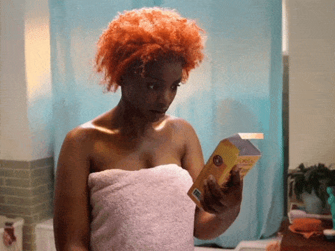 black woman with color treated hair looking at hair dye box