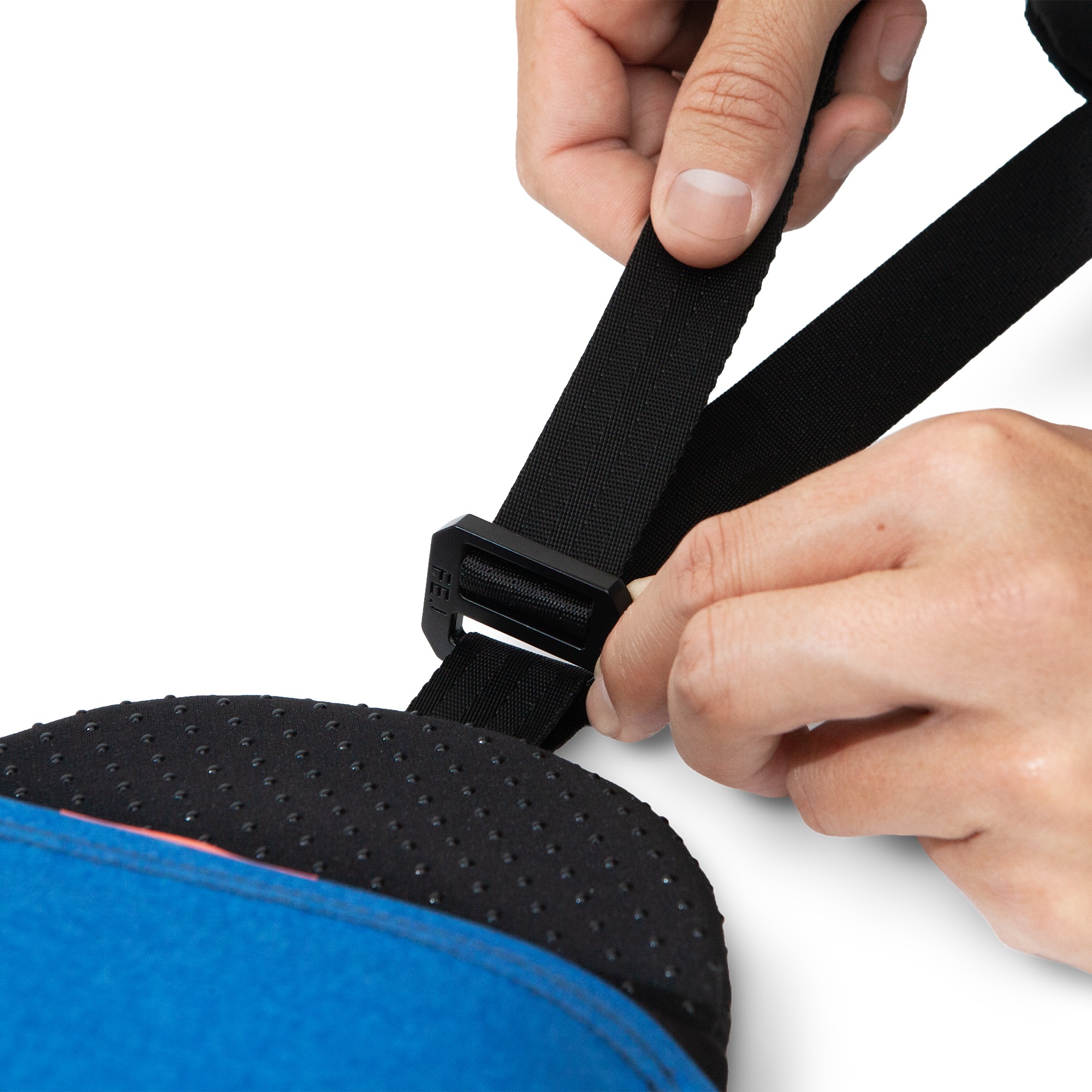 Two hands pulling on the strap and G-hook of a blue and black nap pillow designed for power napping.