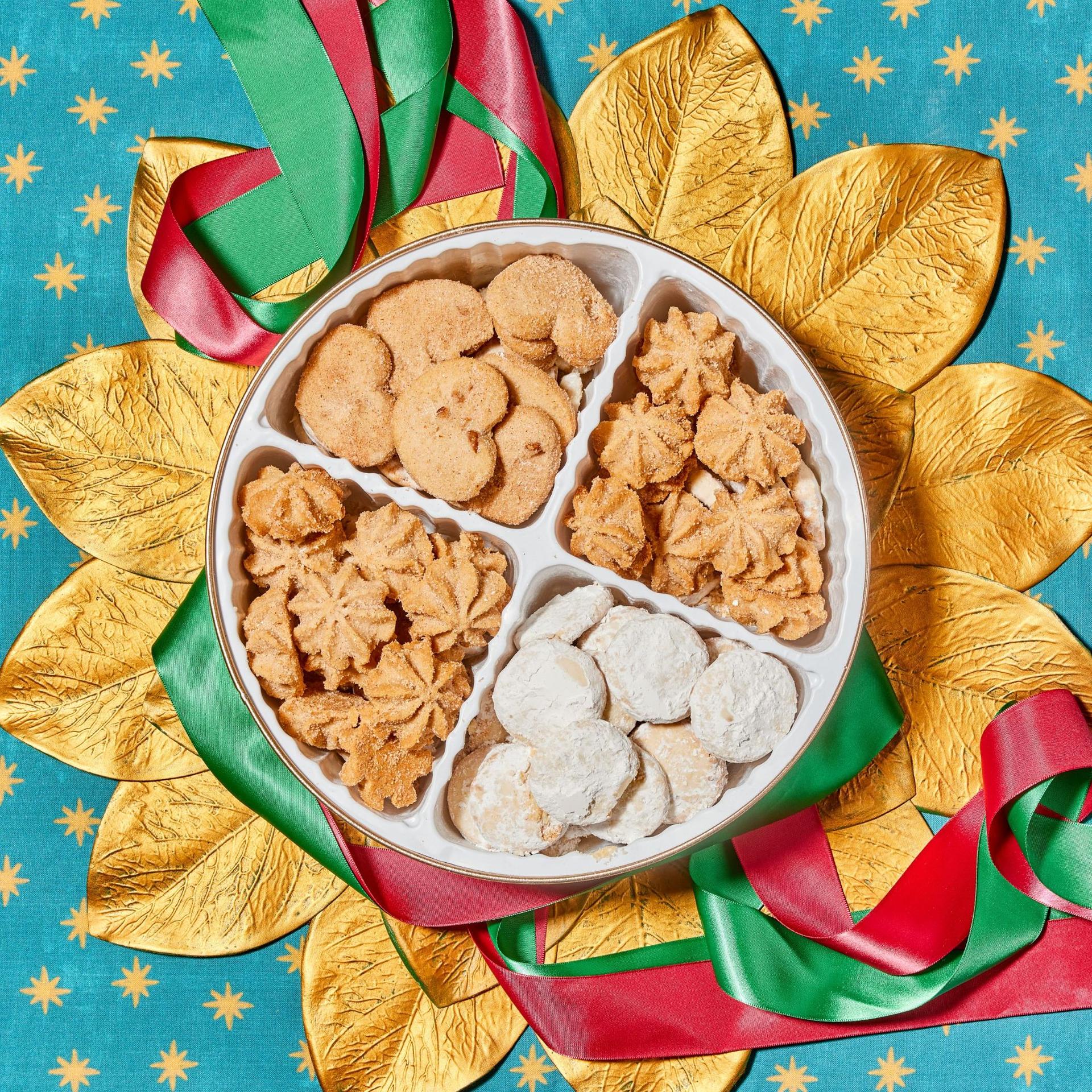 4 cavity cookie tin with three types of mexican cookies against a dark green background