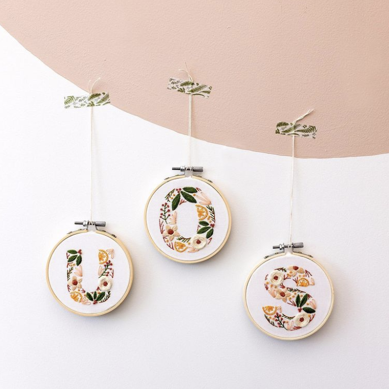 Three Maker's Academy festive alphabet embroidery creations hang on the wall.