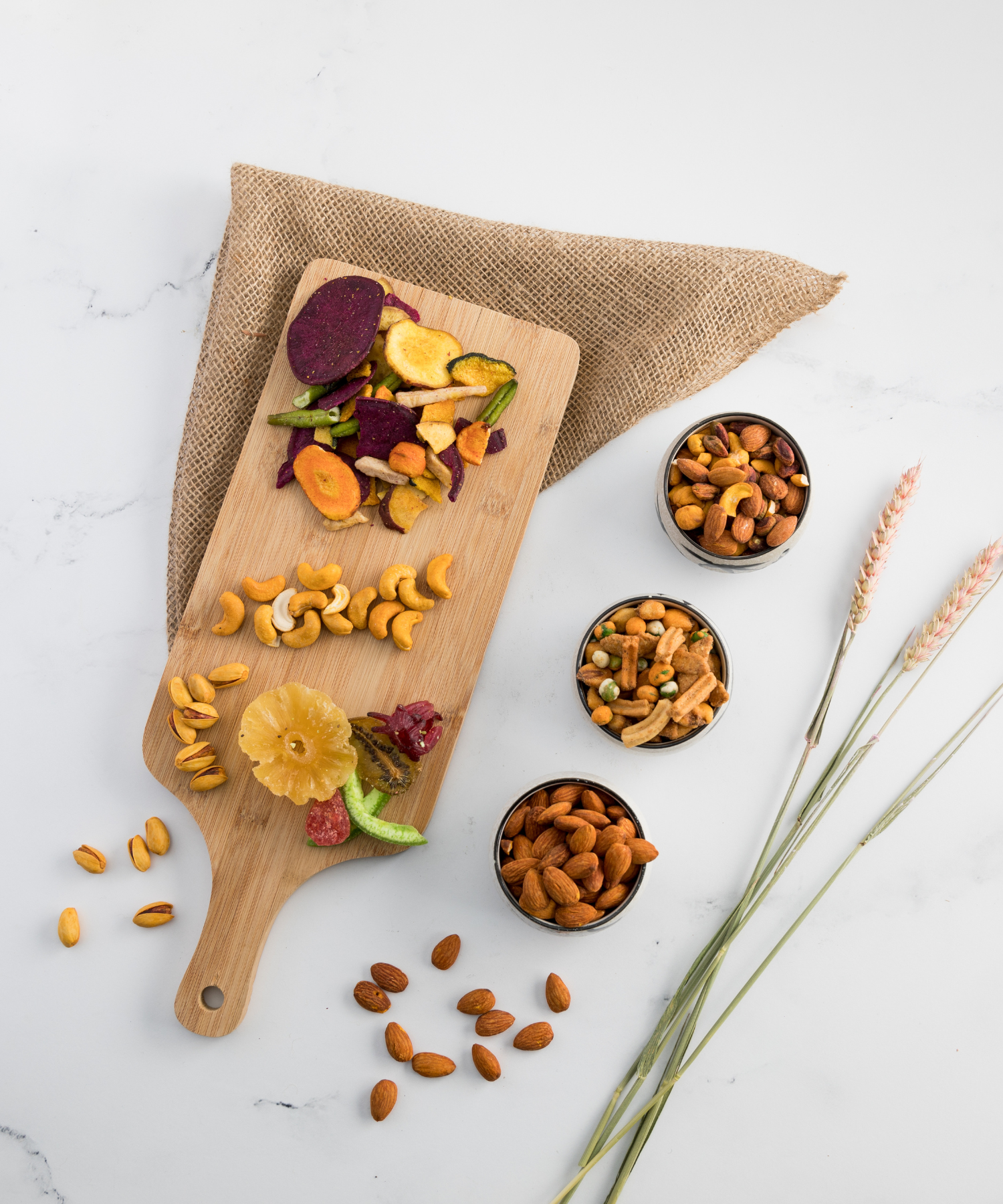 A rustic wooden board featuring a variety of dried fruits and nuts, with small bowls of mixed nuts placed alongside, creating a balanced and appetizing snack display.