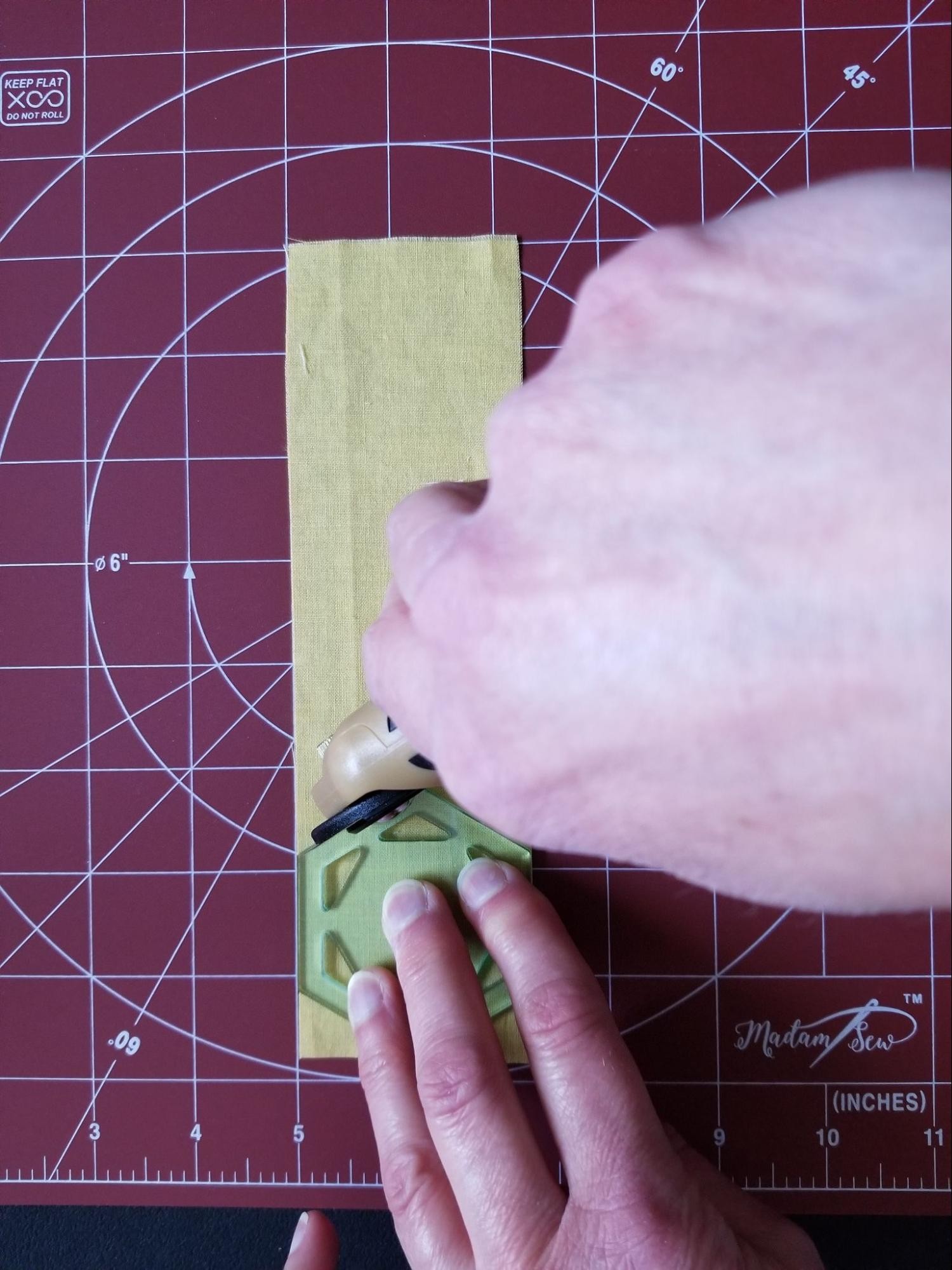 Cutting the first hexagon shape using a fabric strip and a hexagon quilt template.