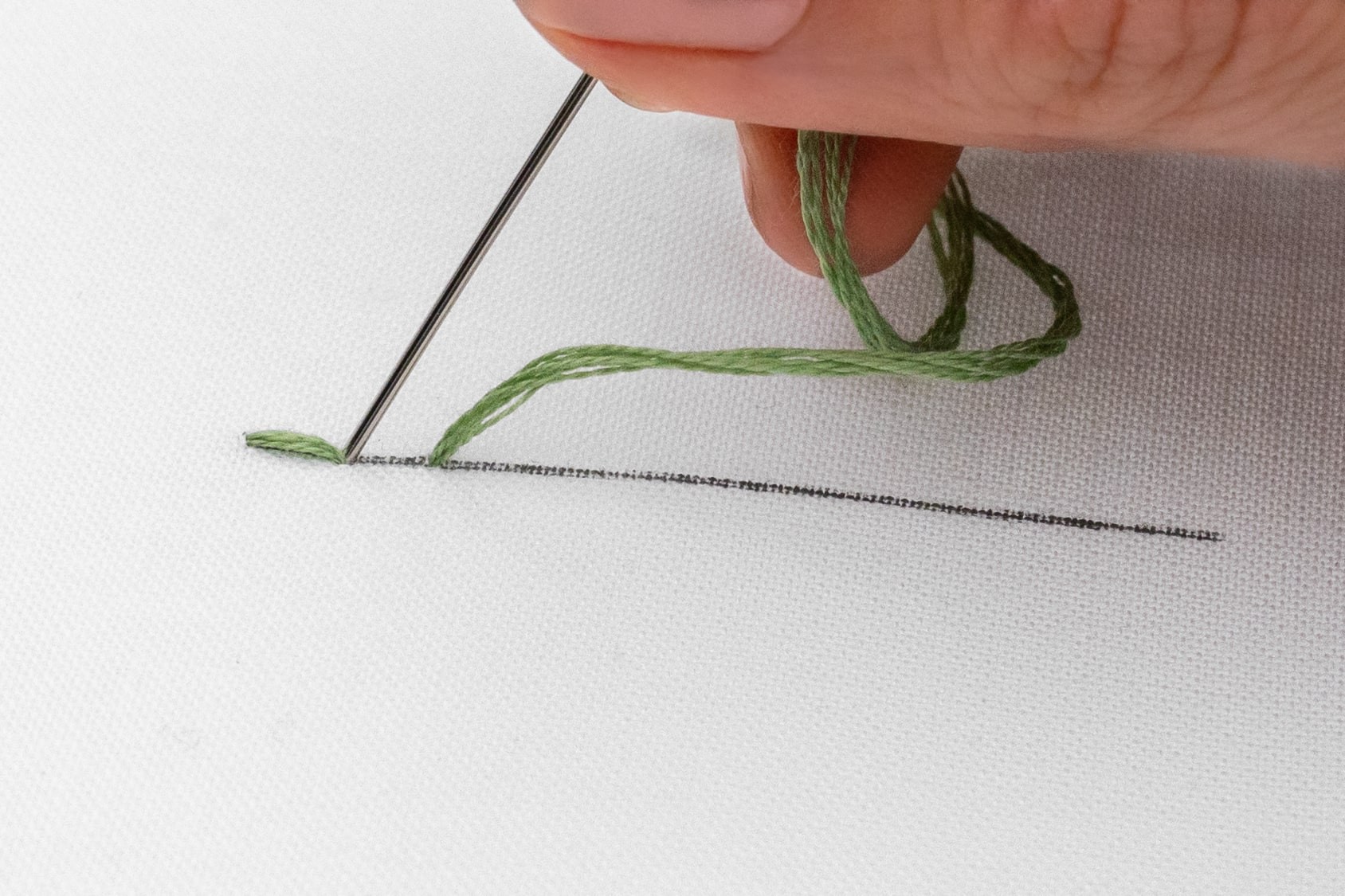 A needle is brought down to create a second stitch,