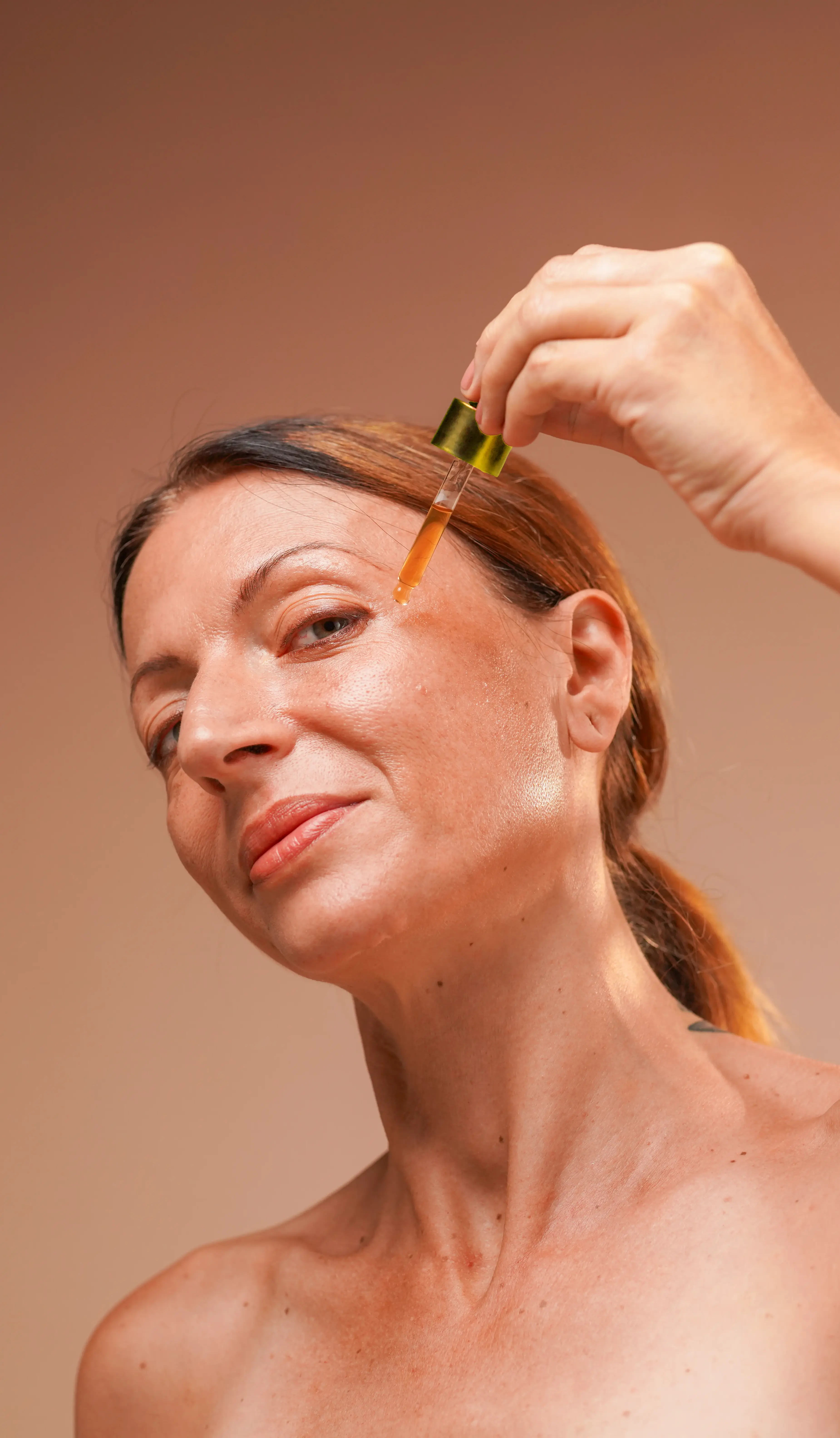 woman applying oil/serum on her face with a dropper