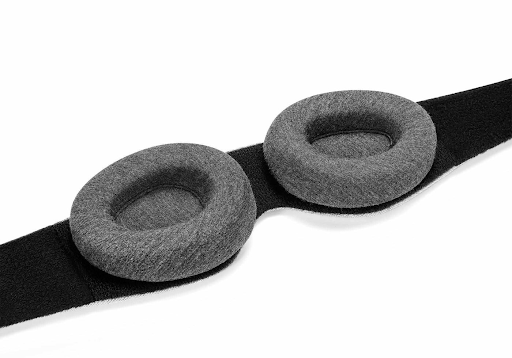 The black interior of a contoured sleep mask with a pair of convex, tapered eye cups.