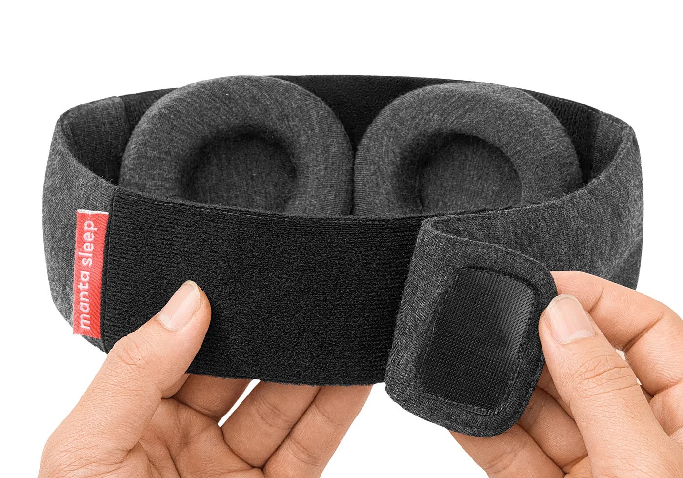 The back portion of the head strap of a weighted sleep mask with hands holding the fastener.