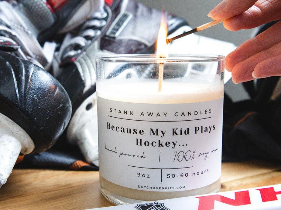 A white candle sits on a table with a pair of ice skates and a hockey stick. Because my kid plays hockey....