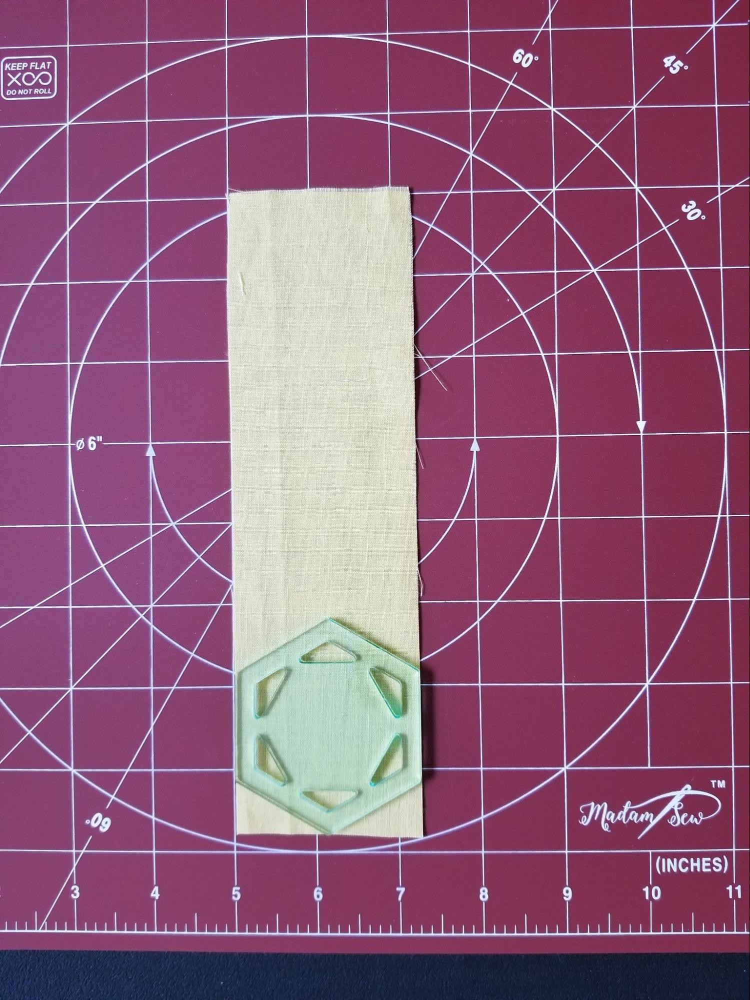 Showing how to align a hexagon quilt template on a fabric strip before cutting.