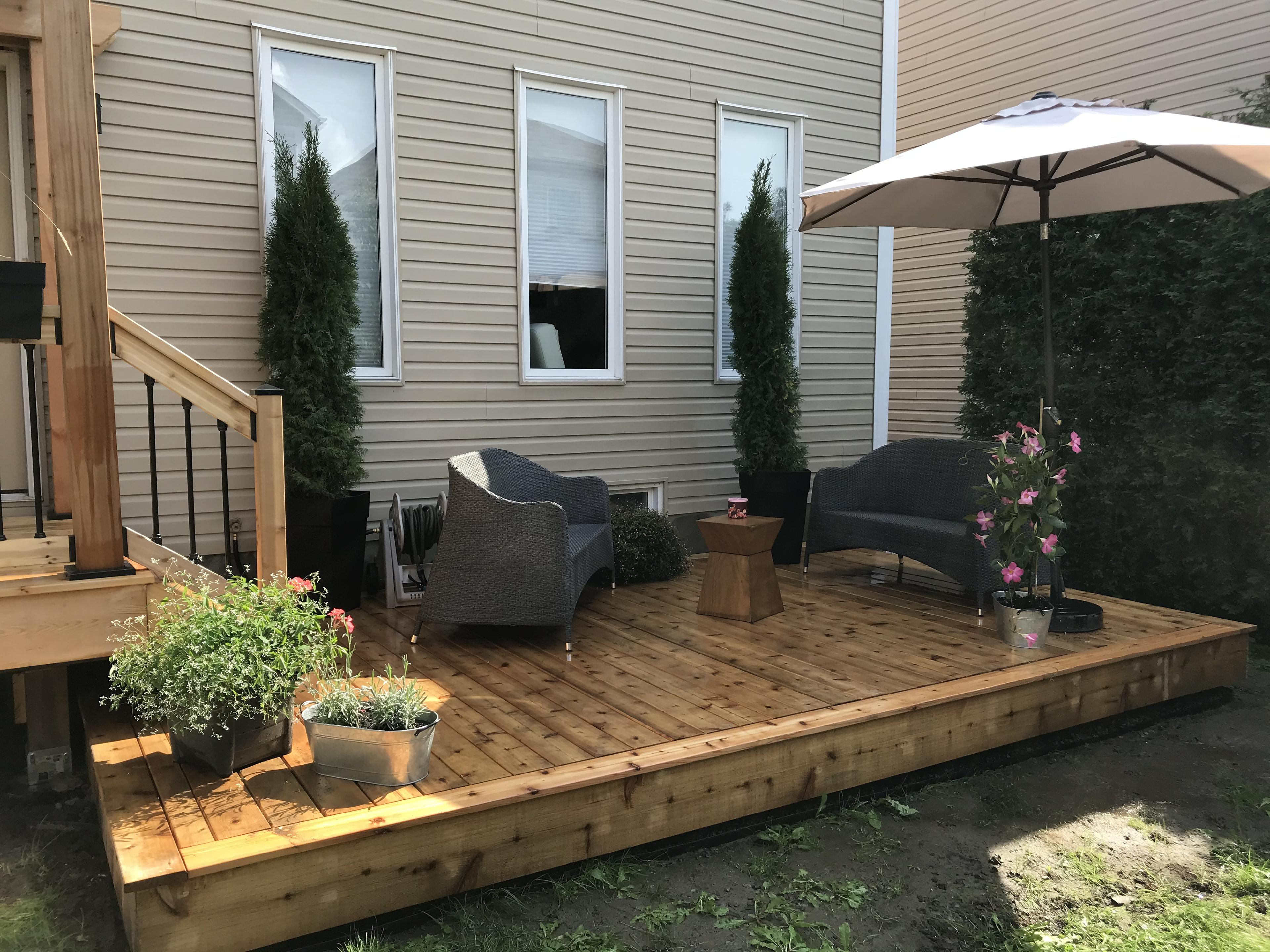 Low level wooden deck with patio furniture potted plants and an umbrella