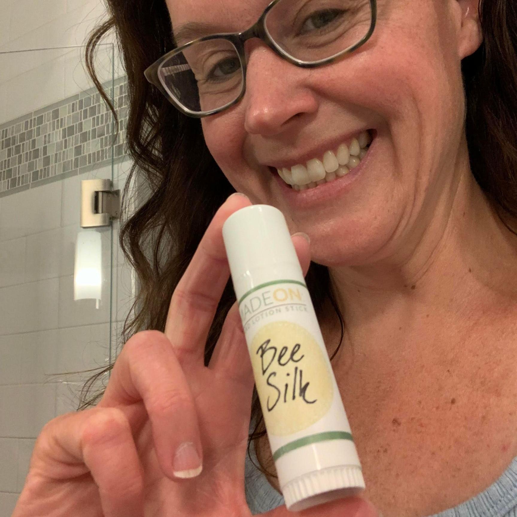 woman holding beesilk lotion stick in bathroom