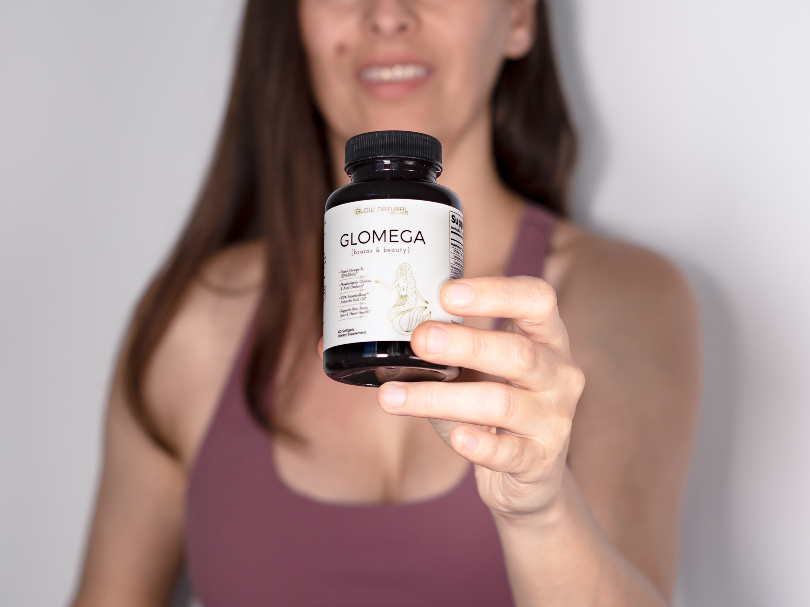 Woman holding a bottle of Glomega omega-3 supplements.