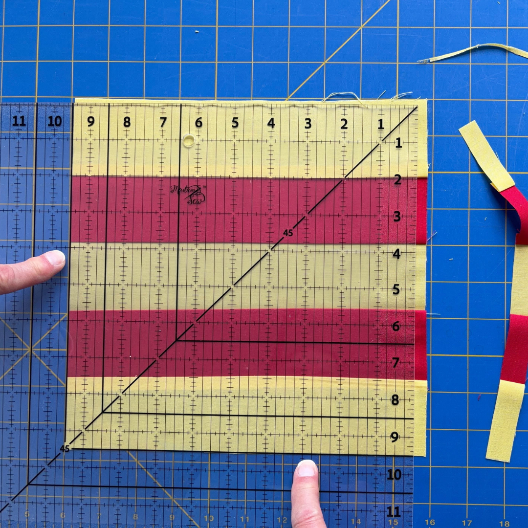 Madam Sew Square-up Quilting Ruler with the 9.5” bold line on the left and bottom edges of the quilt block.