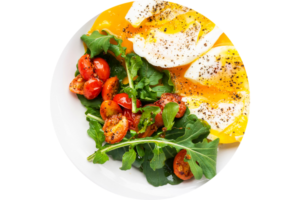 circular image with over easy eggs, roasted tomatoes, and leafy greens