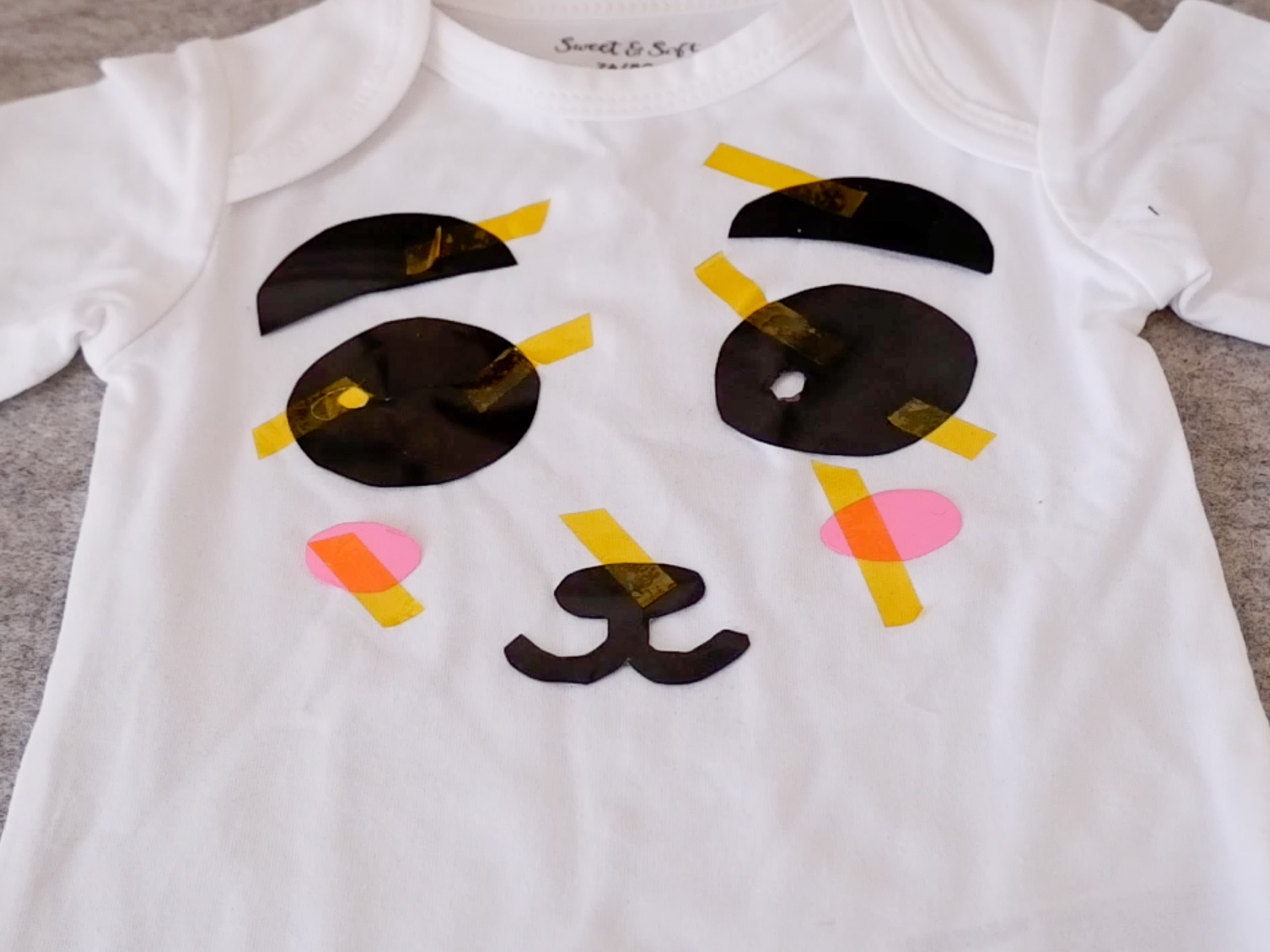 heat transfer vinyl pieces with heat tape on a baby romper