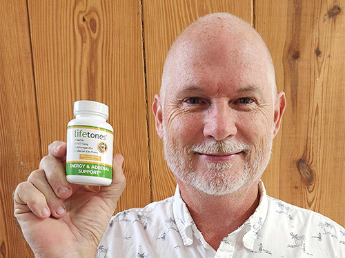 Senior man smiling and holding up Energy & Adrenal Support Capsules